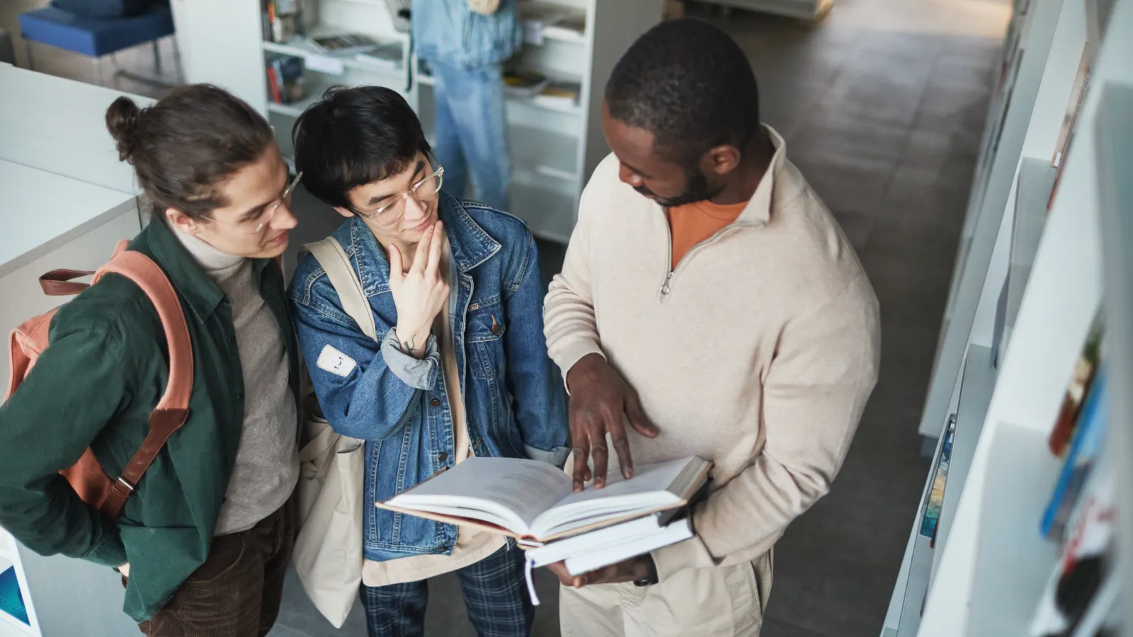 Students discussing a book together in a library