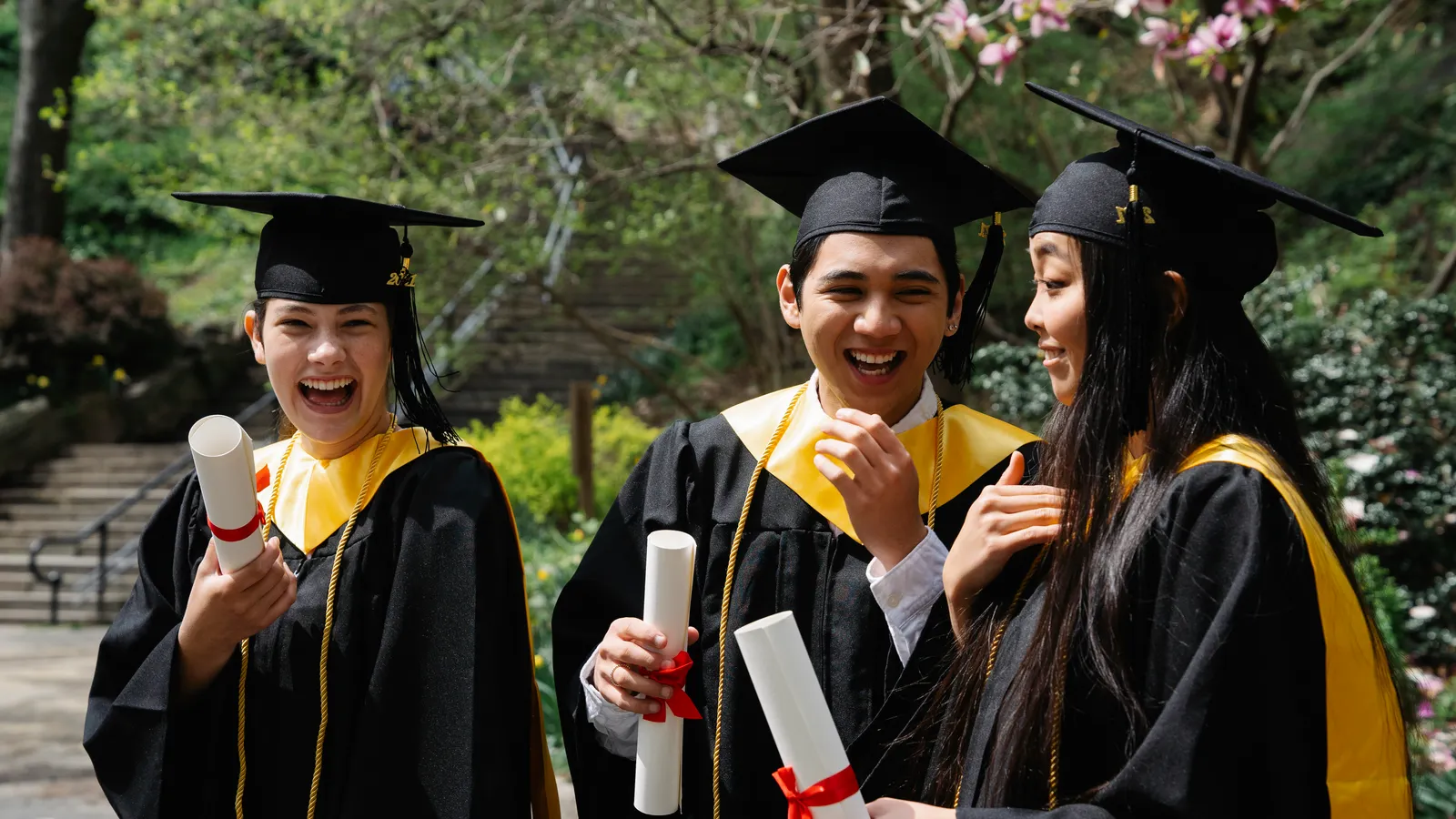 Graduates celebrating outdoors while holding their diplomas