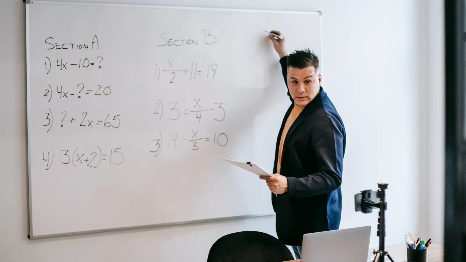 A teacher explaining a mathematics lesson on a whiteboard