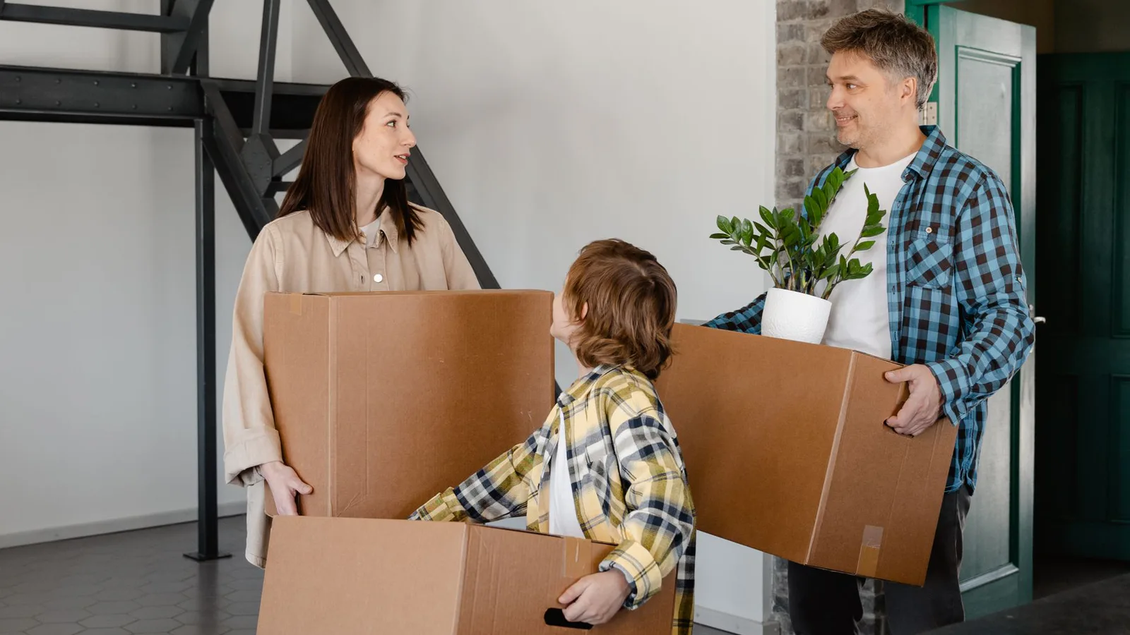 A family carrying moving boxes into a new home
