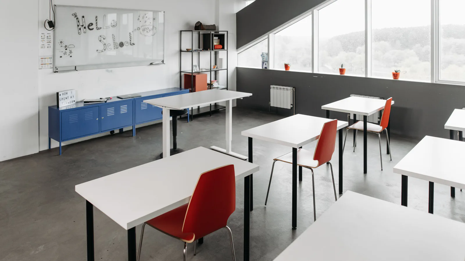 Empty classroom with desks, chairs, and daylight from large windows
