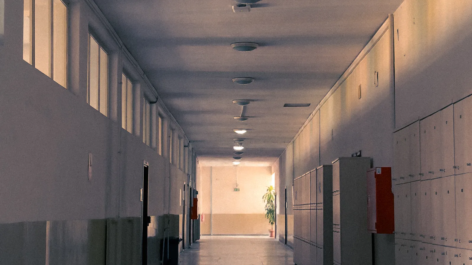 An empty school corridor with lockers and warm lighting